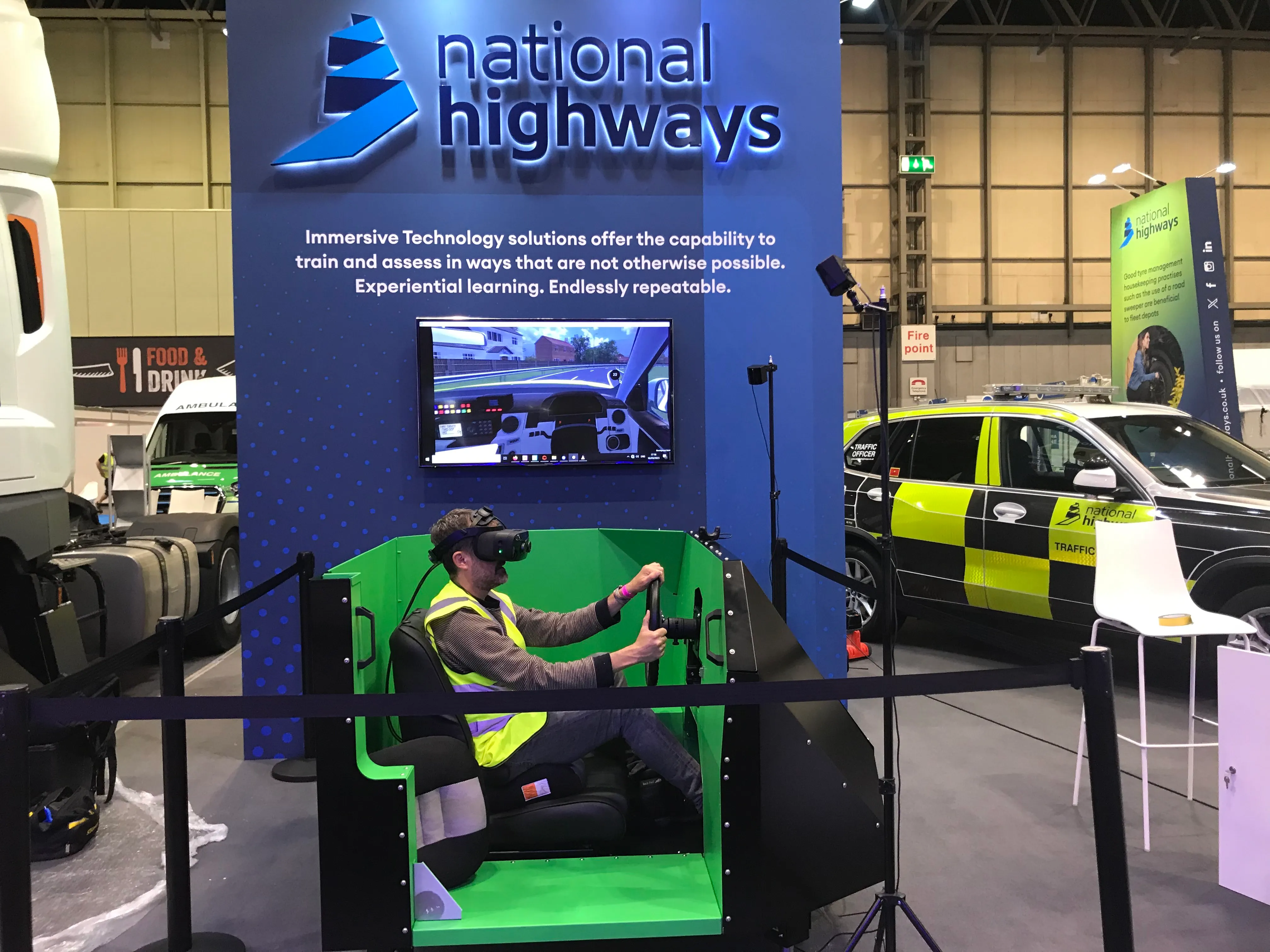 A person sitting in a black and green motion platform wearing a VR headset.